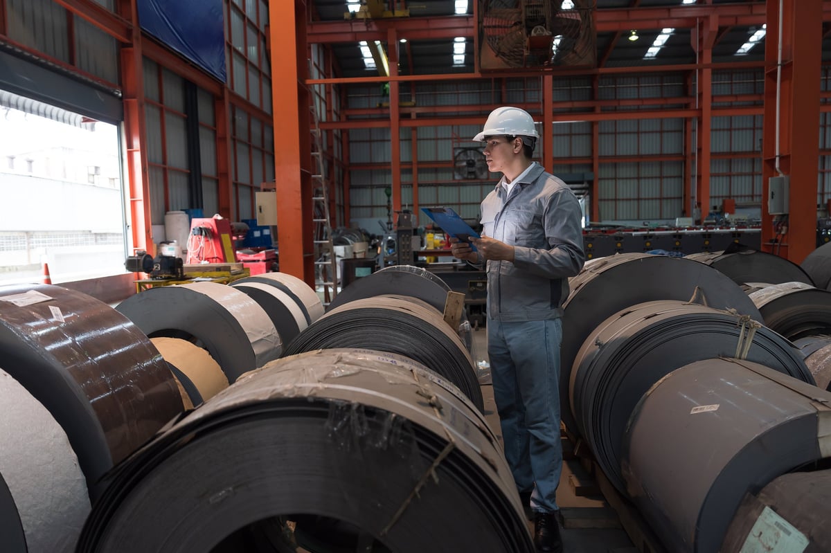 Factory worker inspecting a hot rolled steel coil during quality checks
